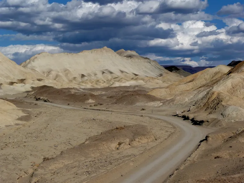 An unpaved road winds through the yellow hills of Twenty-mule Team Canyon.