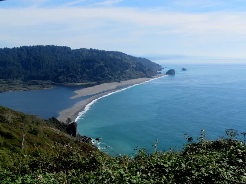 Blue-green ocean and a sandspit at the mouth of a river.