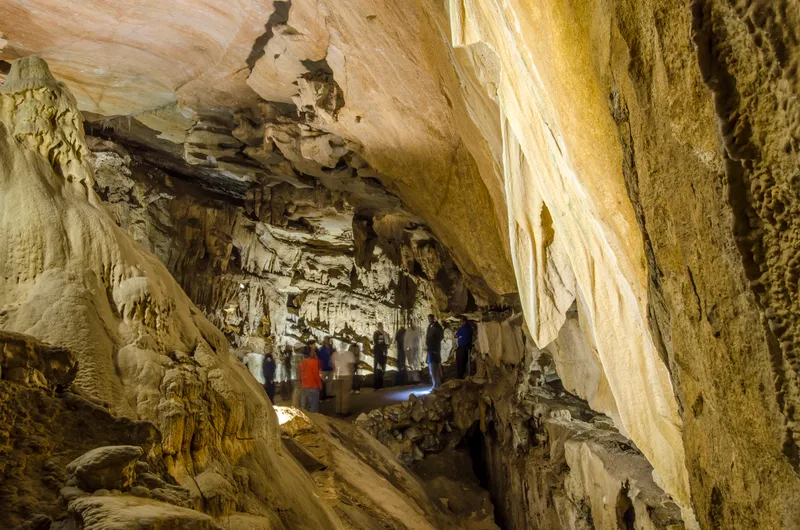 A large room made of marble walls with a group of 9 people in the distance